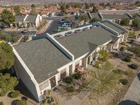 Henderson apartment for rent - A large building with a grey roof is surrounded by trees and other buildings.