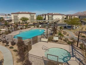 Las Vegas apartment for rent - A pool surrounded by a fence and a sign in front of apartment buildings.
