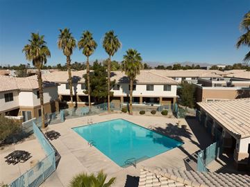 Las Vegas apartment for rent - A swimming pool surrounded by palm trees and buildings.