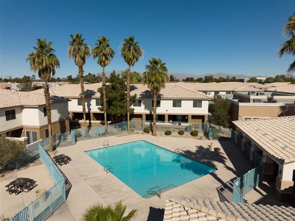 Las Vegas apartment for rent - A swimming pool surrounded by palm trees and buildings.