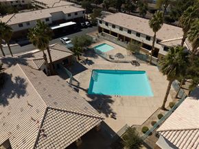 Las Vegas apartment for rent - A swimming pool surrounded by palm trees and apartment buildings.