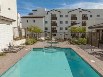 Las Vegas apartment for rent - A swimming pool in a courtyard surrounded by chairs and buildings.