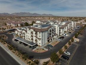 Las Vegas apartment for rent - A large white building with a brown roof is surrounded by a parking lot.