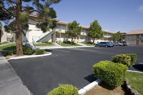 Las Vegas apartment for rent - A parking lot in front of a building with a tree and bushes.