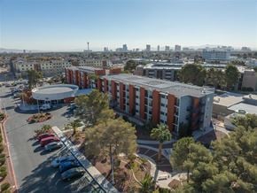 Las Vegas apartment for rent - A large building with a red roof and a parking lot in front of it.