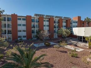 Las Vegas apartment for rent - A building with red pillars and a white roof is surrounded by greenery.