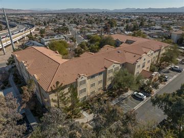 Las Vegas apartment for rent - A large building with a red roof is surrounded by trees and a parking lot.