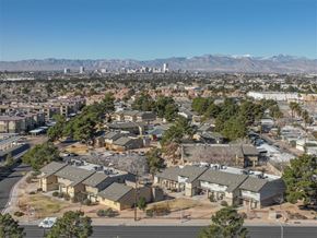 Las Vegas apartment for rent - A residential area with houses and trees in the foreground and a city skyline with mountains in the background.