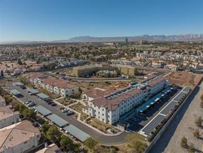 Las Vegas apartment for rent - A large white building with a red roof is surrounded by a parking lot.