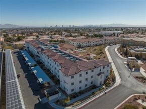 Las Vegas apartment for rent - A large white building with red tile roofs is surrounded by a parking lot and a road.