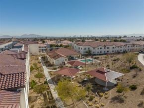 Las Vegas apartment for rent - A view of a housing complex with a swimming pool and a mountain range in the background.