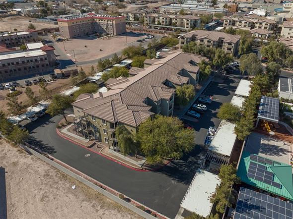 N. Las Vegas apartment for rent - A large building with a red roof is surrounded by other buildings and trees.
