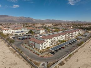 Las Vegas apartment for rent - A large white building with a red roof is surrounded by a parking lot and other buildings.