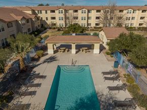 Las Vegas apartment for rent - A swimming pool surrounded by chairs and a building in the background.