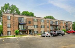 Grand Forks apartment for rent - A parking lot in front of a brick apartment building with cars parked.