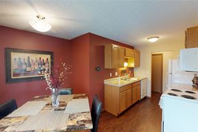 Grand Forks apartment for rent - A kitchen with a table and chairs in front of a red wall.