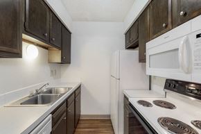 West Des Moines apartment for rent - the preserve at ballantyne commons apartment kitchen with white appliances and dark cabinets