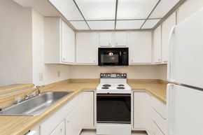 West Des Moines apartment for rent - an empty kitchen with white cabinets and a stove and microwave