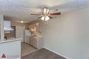 Plattsmouth apartment for rent - an empty kitchen with a ceiling fan and a kitchen with white cabinets