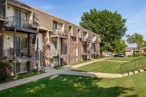 Omaha apartment for rent - a row of brick apartment buildings with balconies and grass and trees