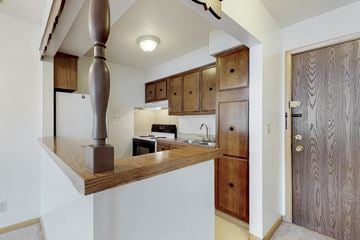 Urbandale apartment for rent - a kitchen with wooden cabinets and a counter top with a stove and sink