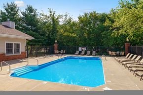 Johnston apartment for rent - a swimming pool with chairs around it in front of a house