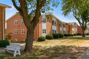 Urbandale apartment for rent - a white bench sits in front of a brick building