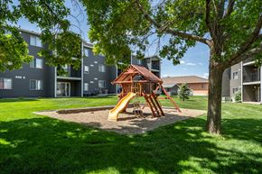 Sioux Falls apartment for rent - A playground with a slide and a wooden structure is surrounded by apartment buildings.