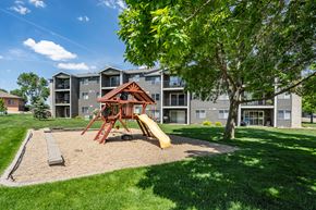 Sioux Falls apartment for rent - A playground with a slide and a wooden structure is in front of apartment buildings.