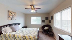 Sioux Falls apartment for rent - A bedroom with a bed, a chair, and a ceiling fan.