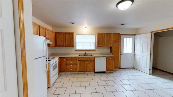 Sioux Falls townhouse for rent - A kitchen with wooden cabinets and white appliances.