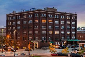 Omaha apartment for rent - a large brick building on a city street at dusk