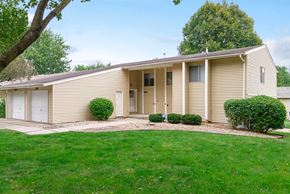 Omaha apartment for rent - the front of a yellow house with a lawn and a driveway