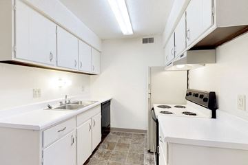 Urbandale apartment for rent - a kitchen with white cabinets and a stove and a sink
