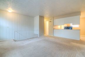 Omaha apartment for rent - the living room and kitchen of an empty apartment with white walls and carpeting