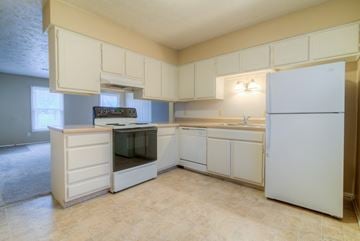 Omaha apartment for rent - a kitchen with white cabinets and a stove and refrigerator