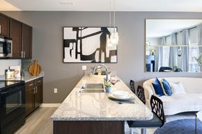 Carmel apartment for rent - A modern kitchen with a large island and a dining area with a couch at Sophia Square Apartments, Carmel, IN