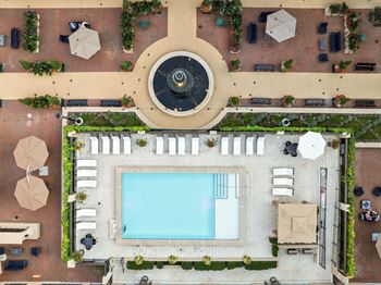 A pool surrounded by a patio with chairs and plants.