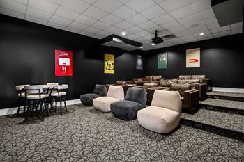 A room with black walls and a patterned carpet with several chairs and a table.