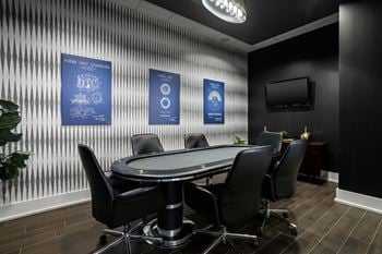 A conference room with a table surrounded by chairs and posters on the wall.