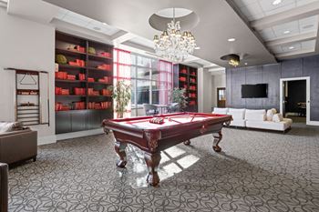 A pool table is in the middle of a room with a grey carpet.