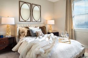 Carmel apartment for rent - A bedroom with a large bed covered in a white fur throw at The Olivia Apartments, Indiana