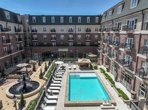 Carmel apartment for rent - A large pool surrounded by a fence and a building in the background at Sophia Square Apartments, Carmel, IN