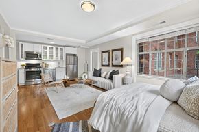 Washington apartment for rent - A well-lit bedroom with a large bed and a kitchen area in the background.