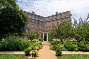 Washington apartment for rent - A large red brick building with a white entrance and a garden in front.