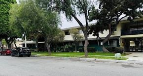 Glendora multi-family for rent - A building sits behind a row of trees.