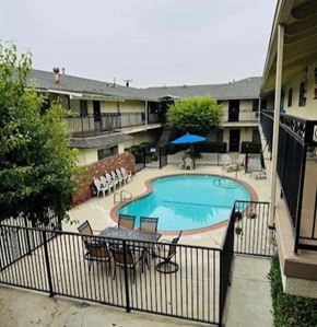 Glendora multi-family for rent - A black fence surrounds a small pool with chairs and an umbrella.