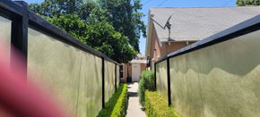 Arcadia apartment for rent - A narrow alley with a wall on one side and a house on the other.