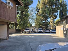 Santa Fe Springs multi-family for rent - A parking lot with cars and a building with an air conditioning unit.