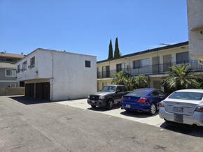 Bellflower multi-family for rent - A parking lot with cars and a building in the background.